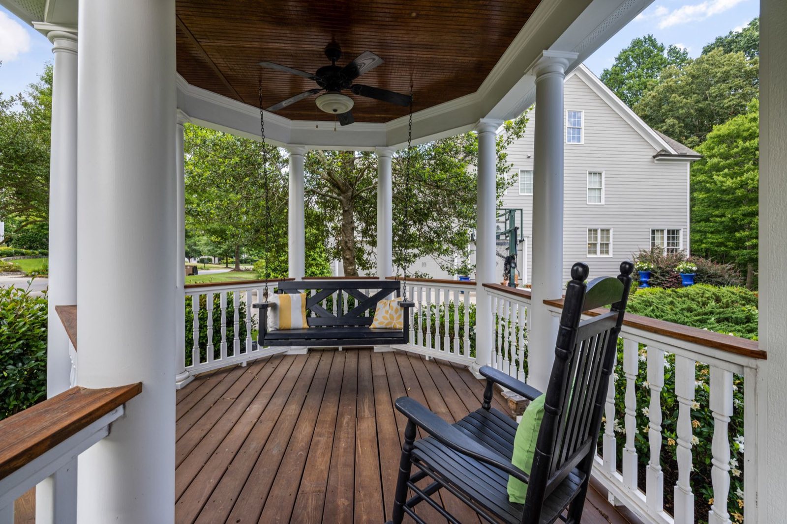 A wraparound porch with a rocking chair and a porch swing