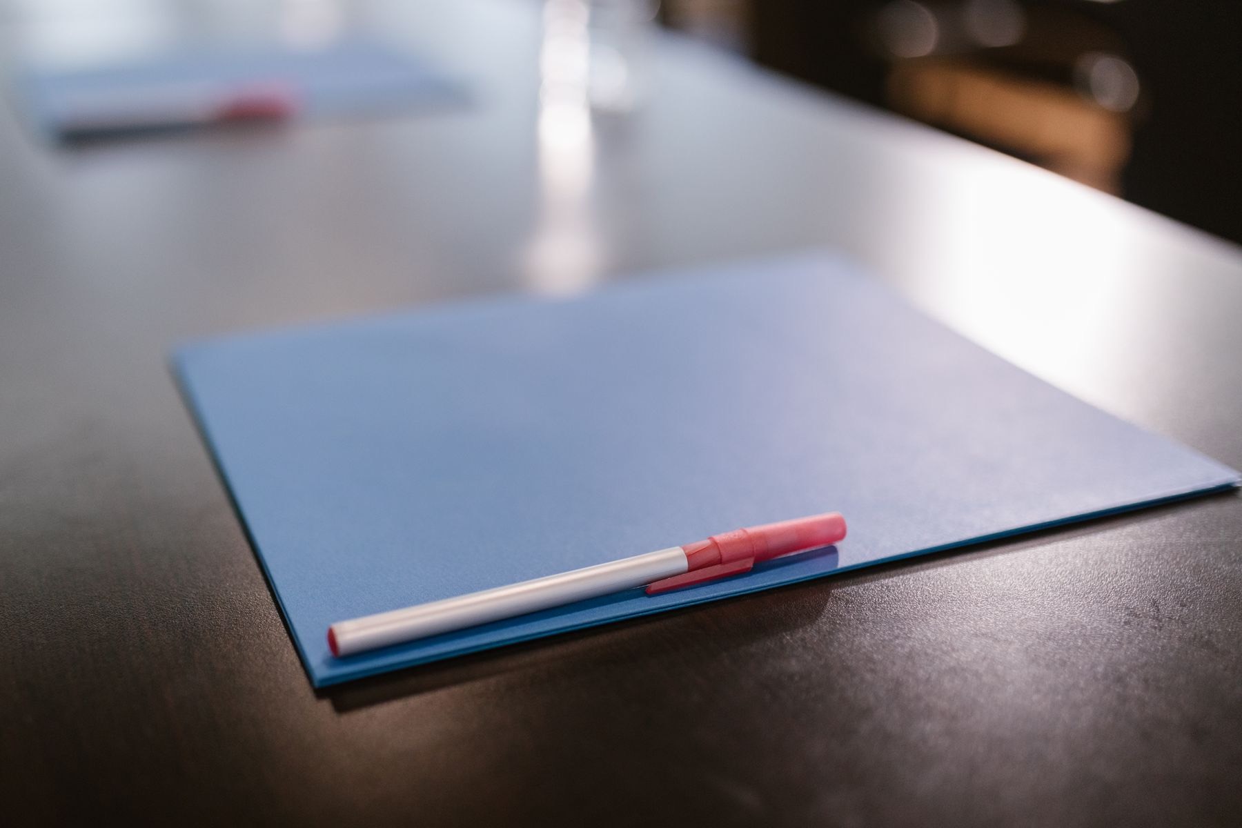 A blue folder with a pen resting on top, on a dark desk