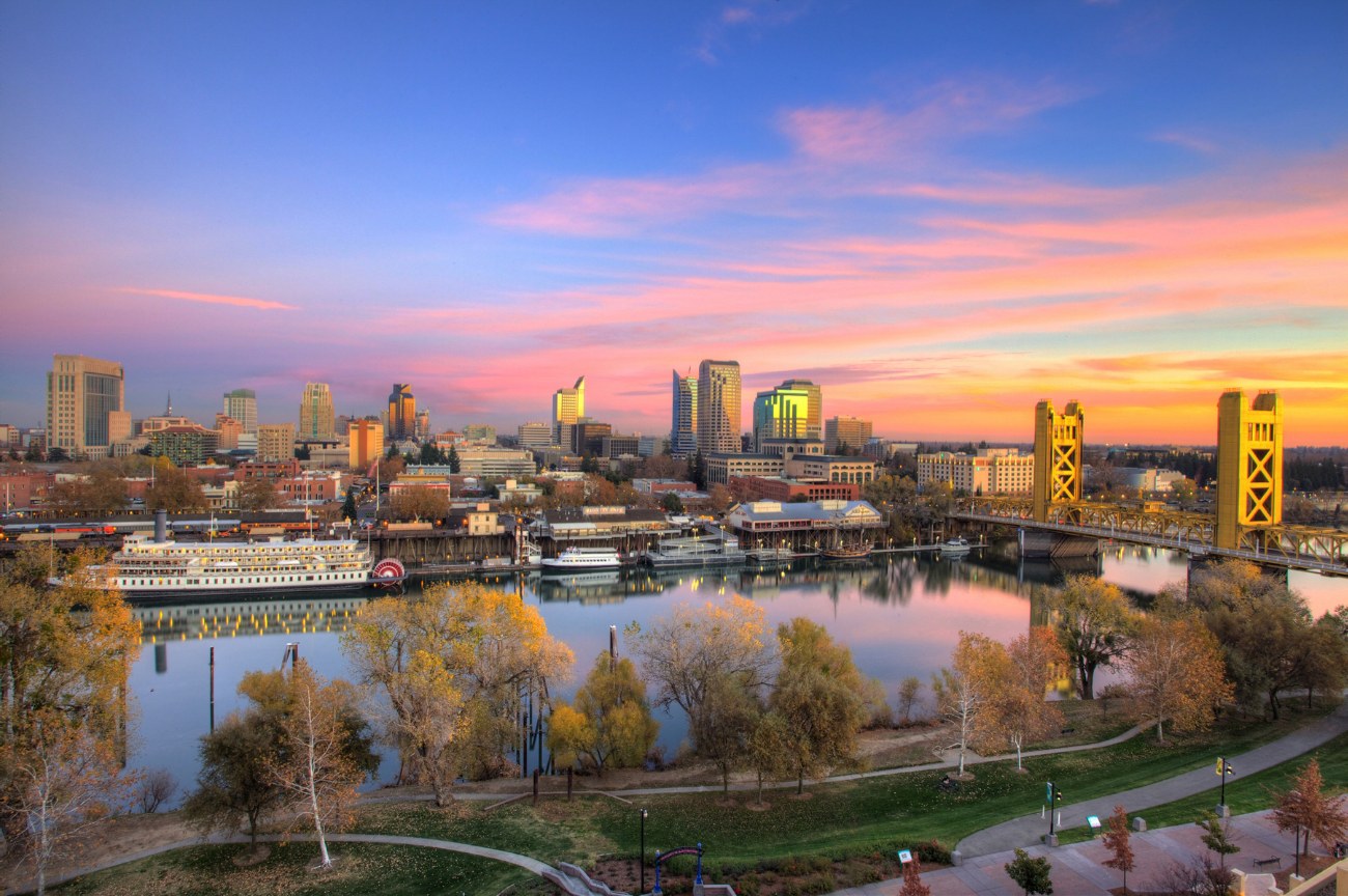 Downtown Sacramento skyline at sunset across the Sacramento River, with the Delta King and Tower Bridge