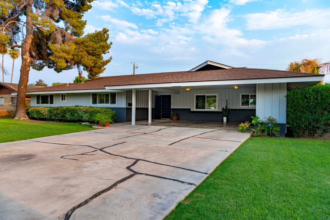 A long, low one-story ranch house with a covered porch and a green lawn
