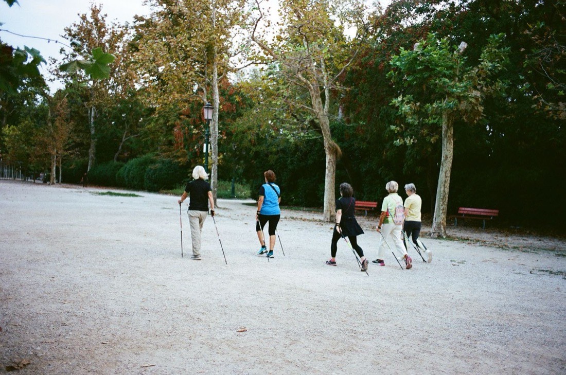 A group of older adults Nordic walking together through a park